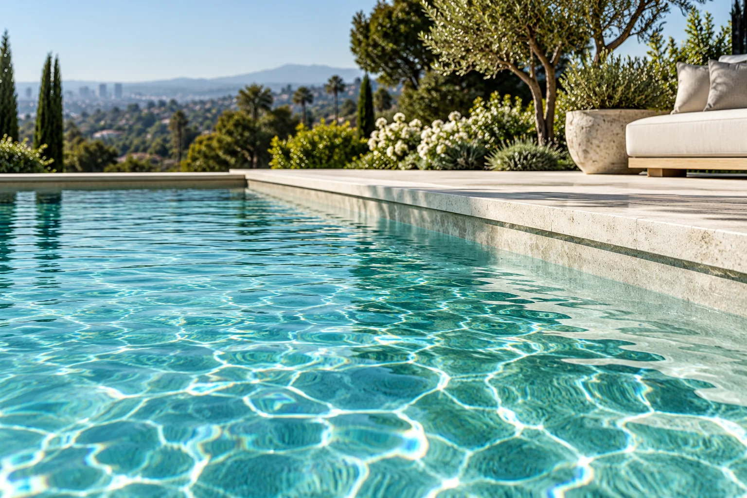 Sunlight moving across clear pool water beside a pale stone edge